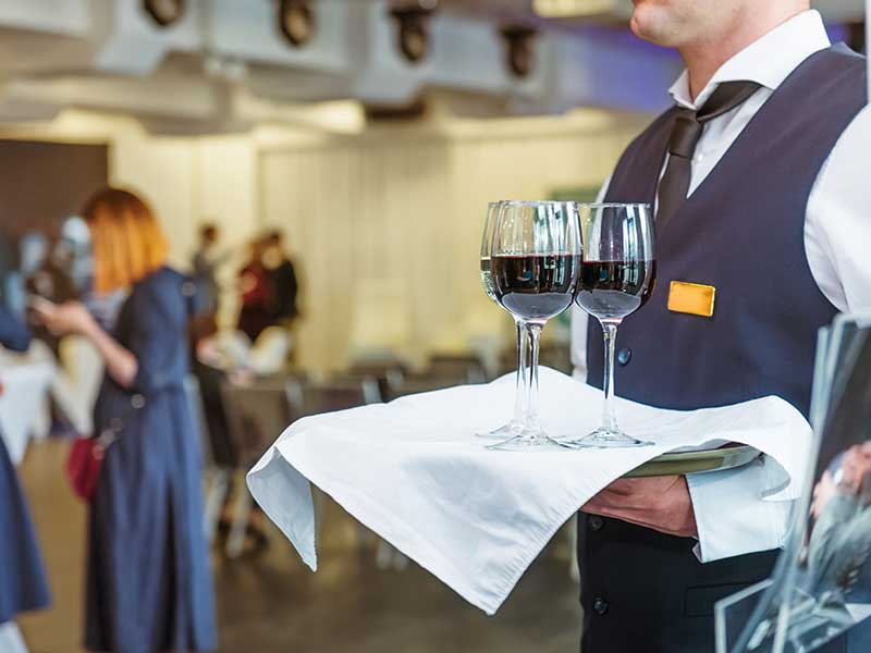 Server carrying two wine glasses on a tray.