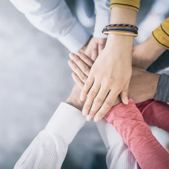 Close up view of people putting their hands together.